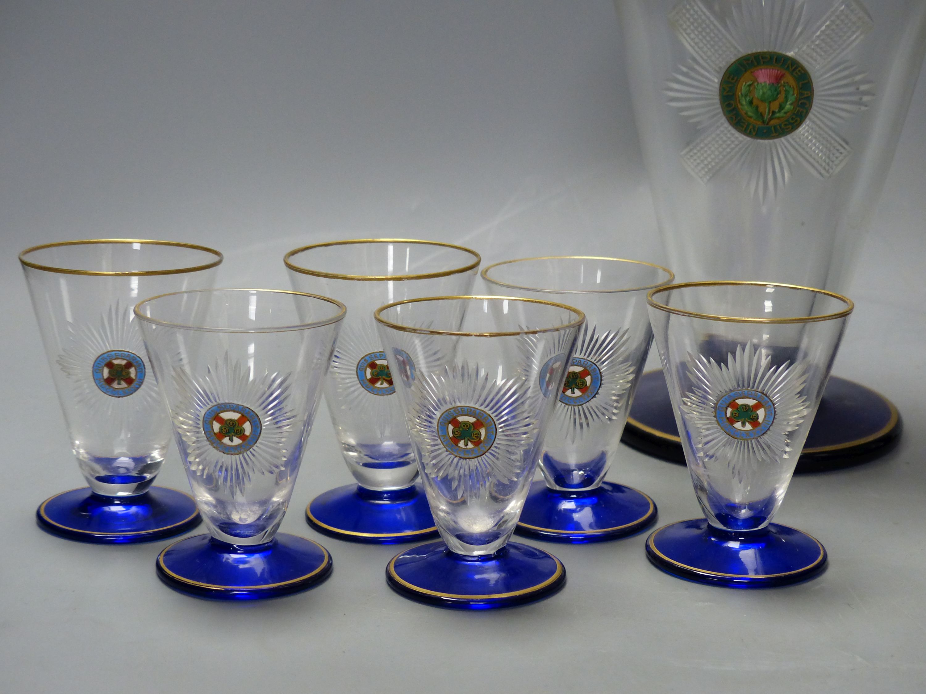 A pair of Art Deco cobalt blue and gilt-mounted tapered glass cocktail shakers, c.1920, enamelled with Black Watch and 4th Royal Irish Dragoon Guards mottos and six matching glasses